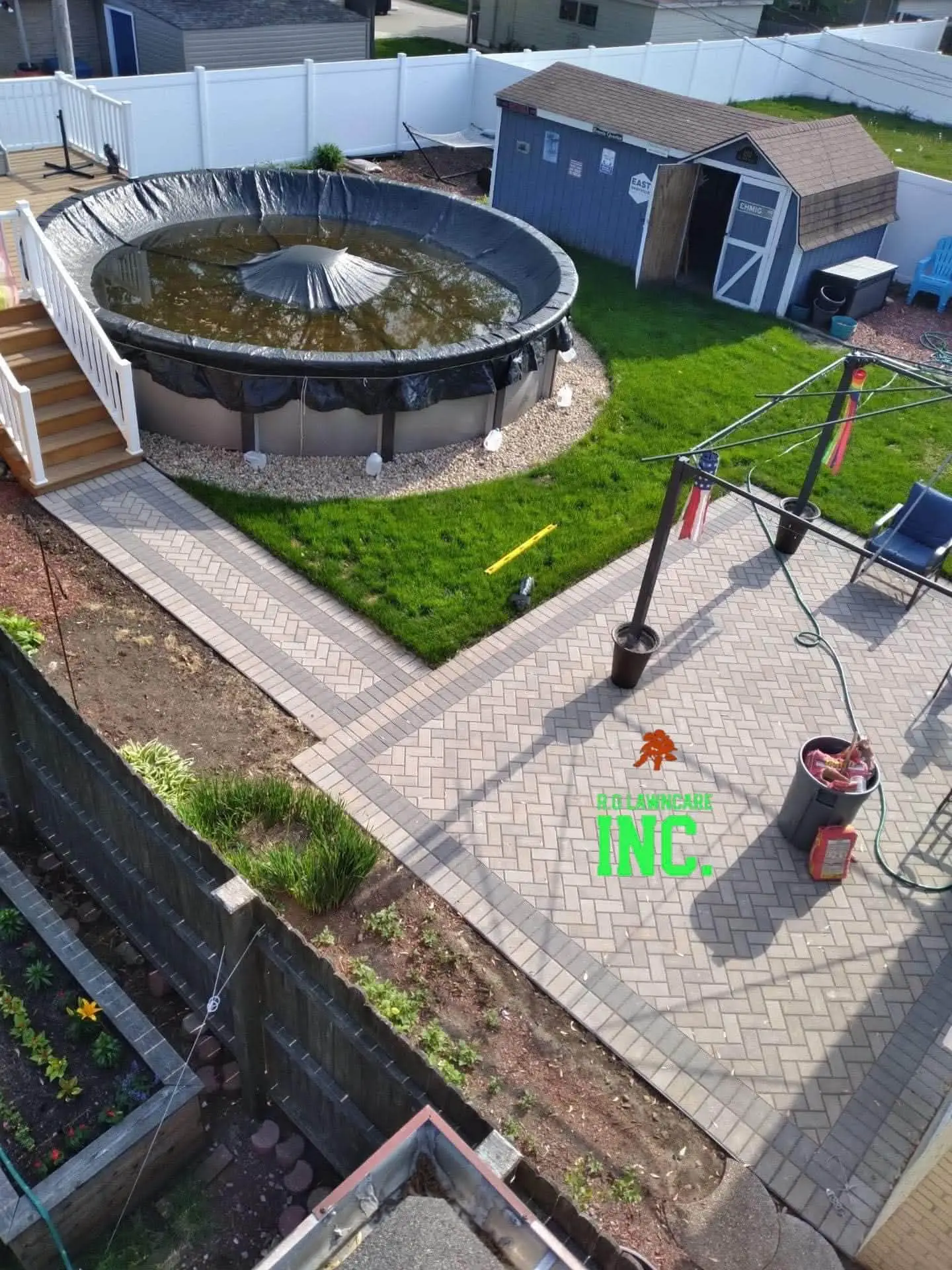 Aerial view of herringbone paver patio and walkway around an above-ground pool